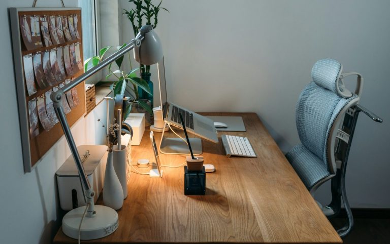 Erfahre mehr auf der Seite Offenes Ohr Online Hellblaue Schreibtischumgebung mit Pflanzen, Laptop und moderner Schreibtischlampe auf einer Eichentischplatte.
